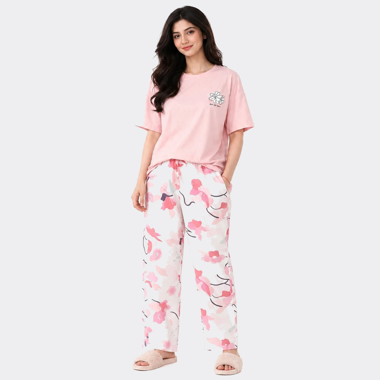 Woman wearing a pink t-shirt and floral pants on a white background