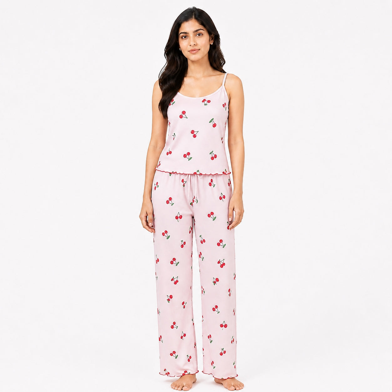 Woman wearing a pink pajama set with cherry pattern on a white background