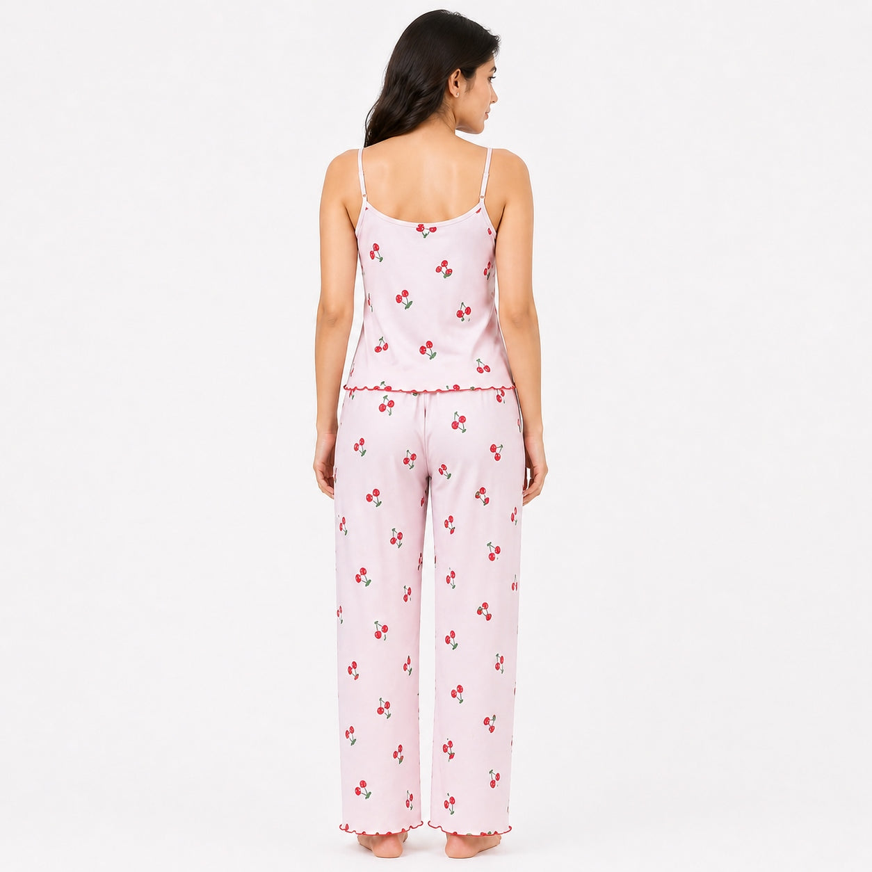 Woman wearing a pink pajama set with cherry pattern on a white background
