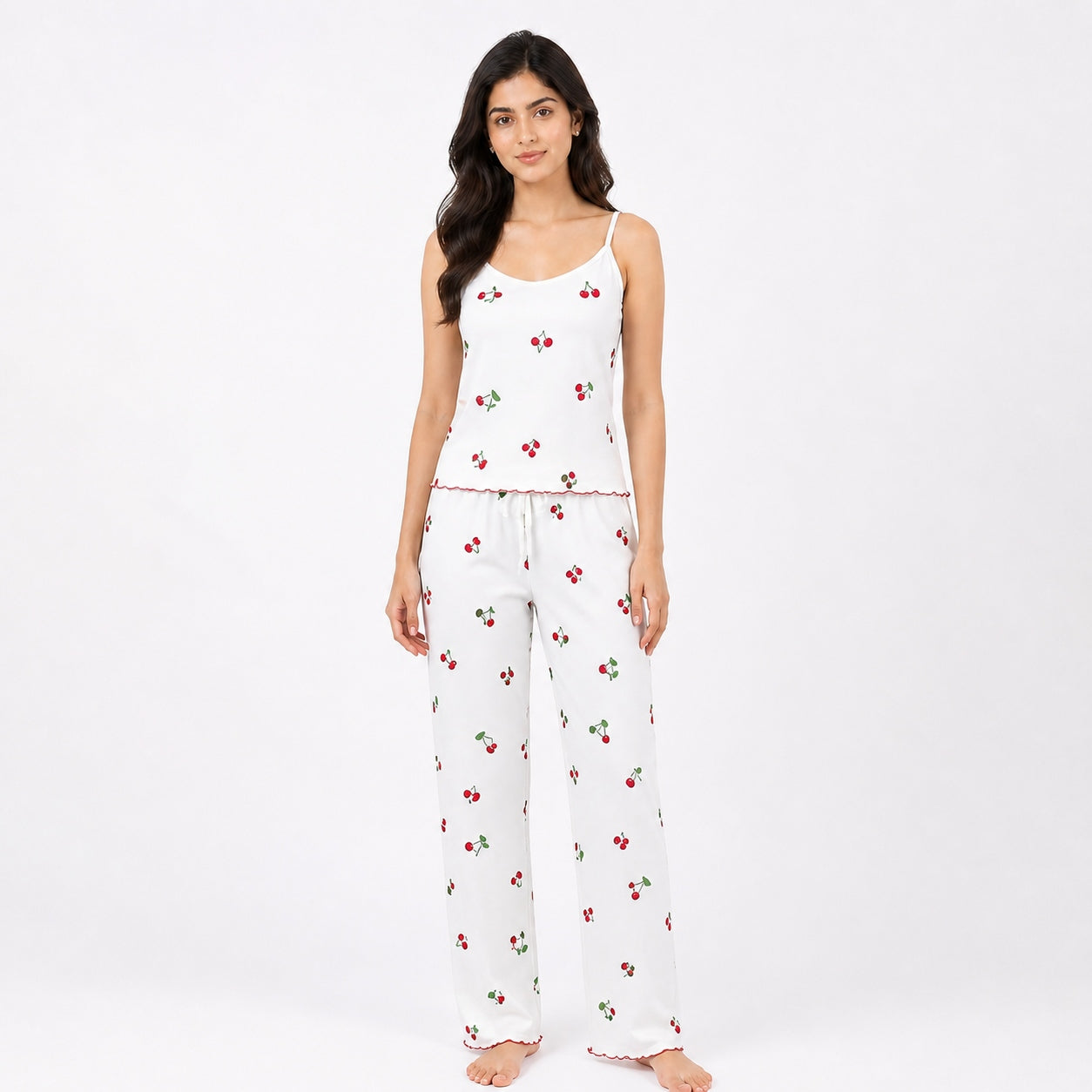 Woman wearing a white pajama set with cherry pattern on a white background