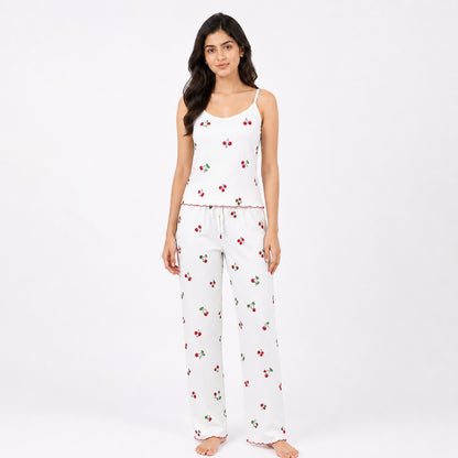 Woman wearing a white pajama set with cherry pattern on a white background