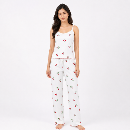 Woman wearing a white pajama set with cherry pattern on a white background